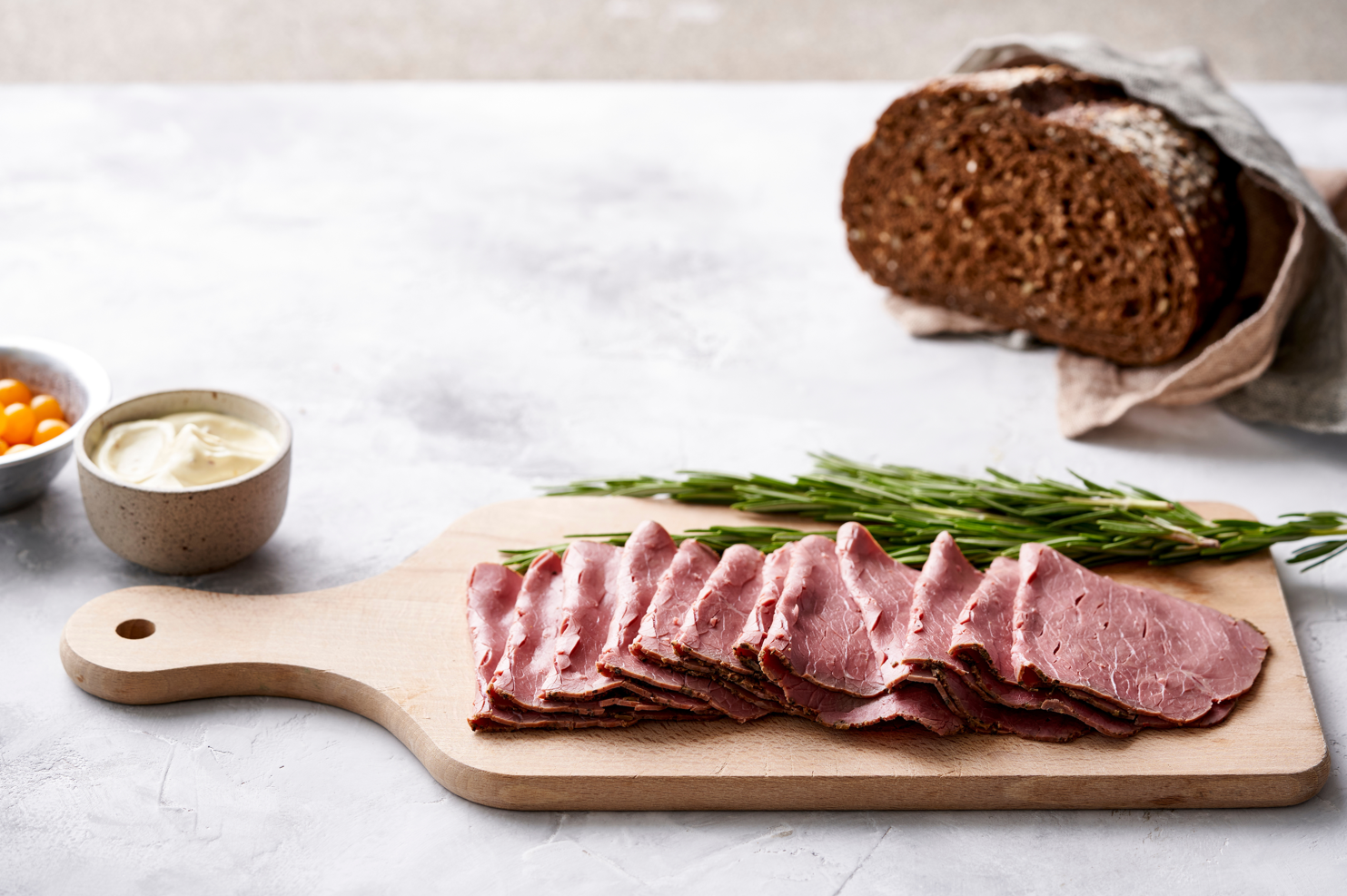 Quelques tranches de viande sont posées sur une planche à découper en bois avec un morceau de pain et de la sauce